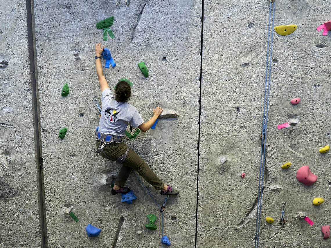 person is top-rope climbing on wall